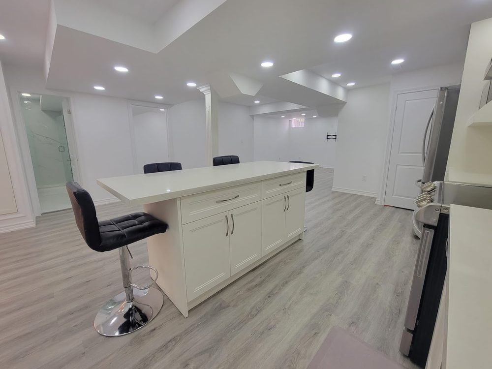 A finished basement kitchen with a white island and bar stools