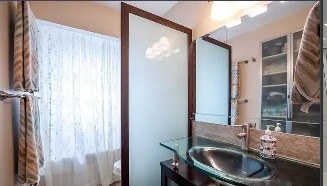 The same bathroom before: dark vanity, old mirror and curtains