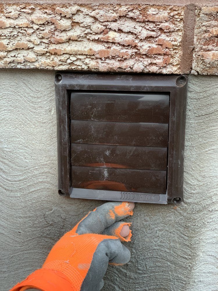 An exhaust fan cover fitted on an exterior stucco wall