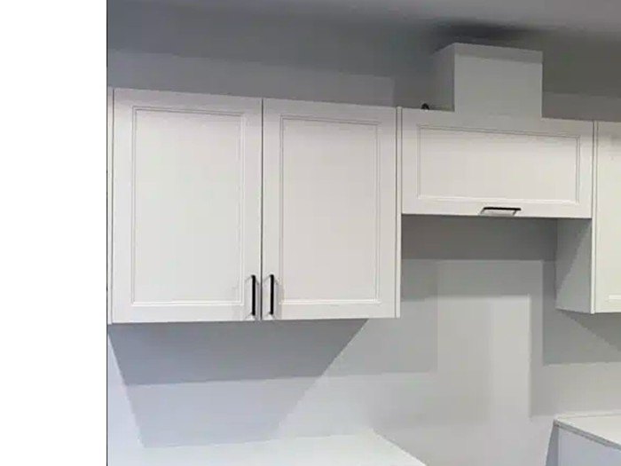 White shaker upper cabinets with a boxed-in range hood surround