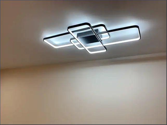 A modern rectangular LED light fixture glowing on a white ceiling