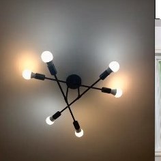 A six-arm black light fixture with bare bulbs installed on a ceiling