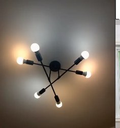 A six-arm black ceiling light fixture with bare bulbs