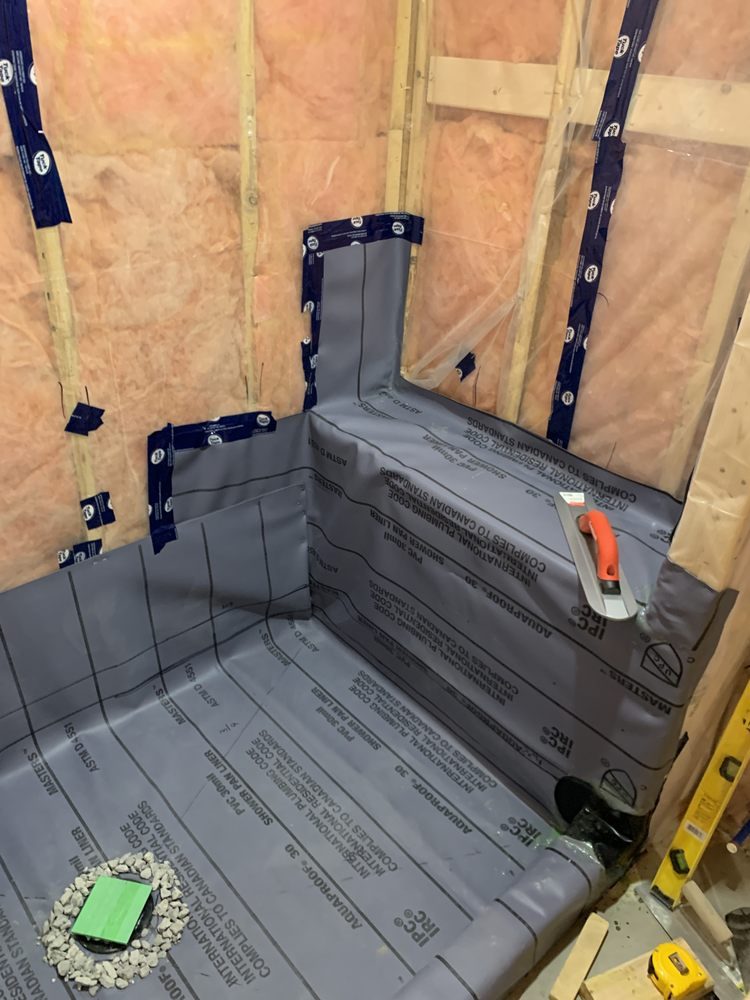 A shower area under construction with insulation, waterproof membrane and a tiled curb